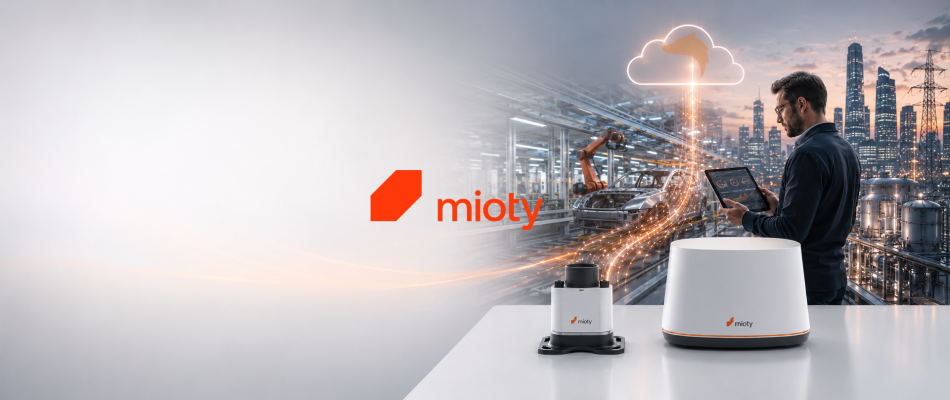 Zwei mioty-Geräte auf einem Tisch, Mann mit Tablet vor Industriekulisse