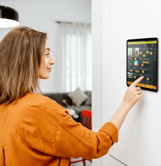 Frau bedient ein LUPUS Smarthome-Display an der Wand